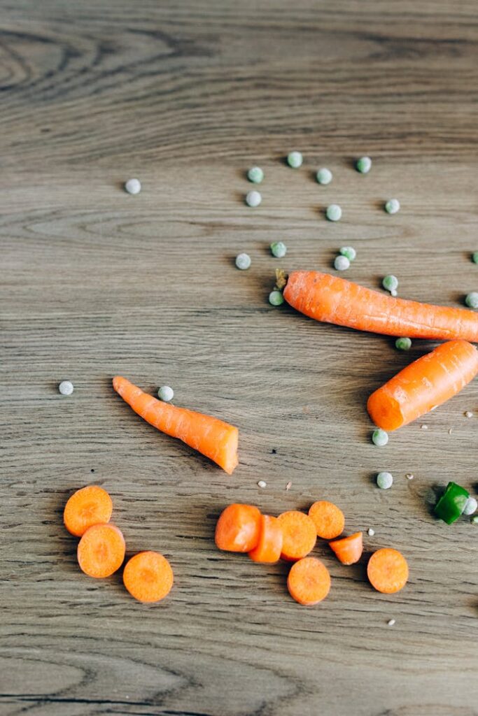 Flatlay of fresh carrots and peas on a wooden surface, perfect for healthy eating themes.