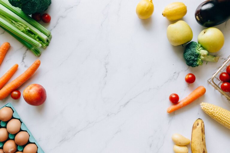 An assortment of fresh fruits and vegetables on a marble background, perfect for healthy lifestyle concepts.